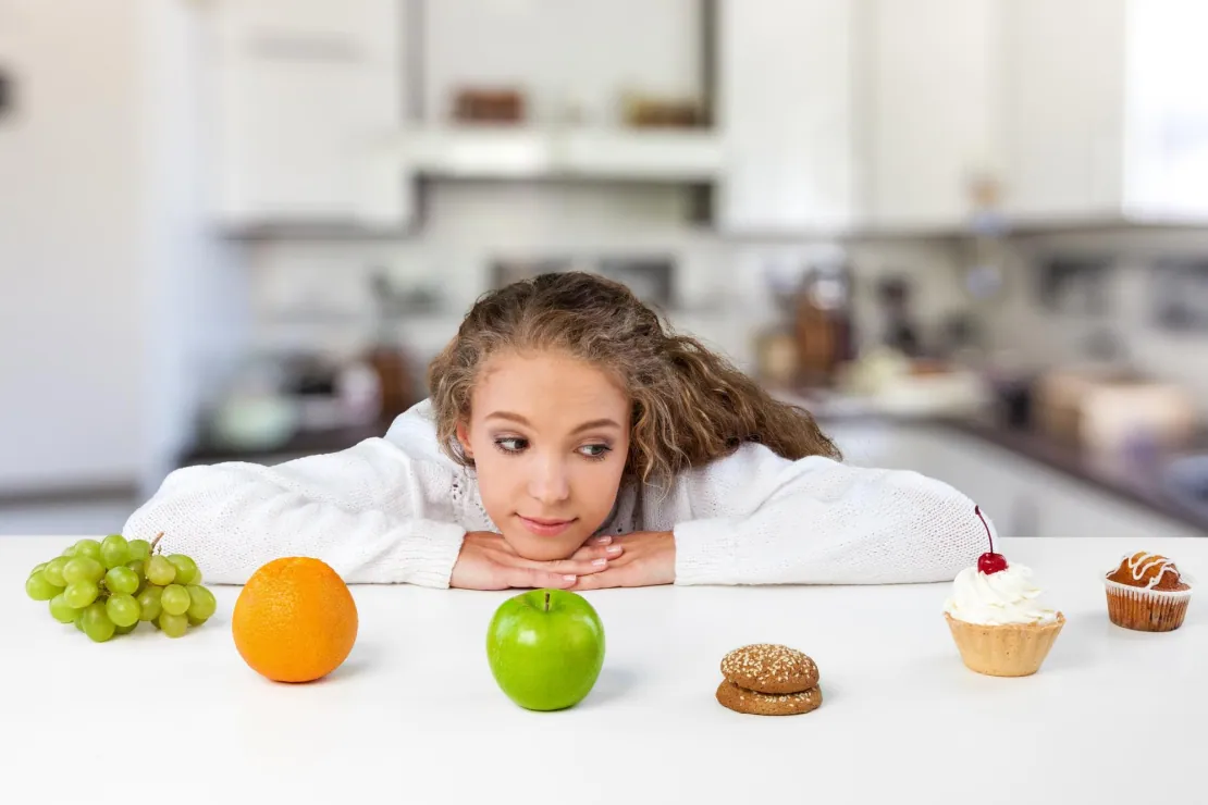 A woman looking at healthy and unhealthy food choices, symbolizing the all-or-nothing mindset.