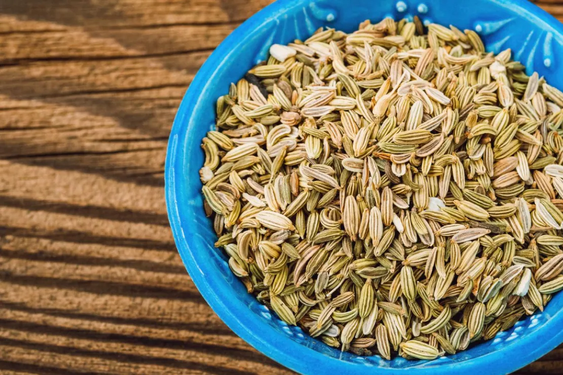Close-up of fennel seeds in a wooden spoon, symbolizing natural digestive aid.