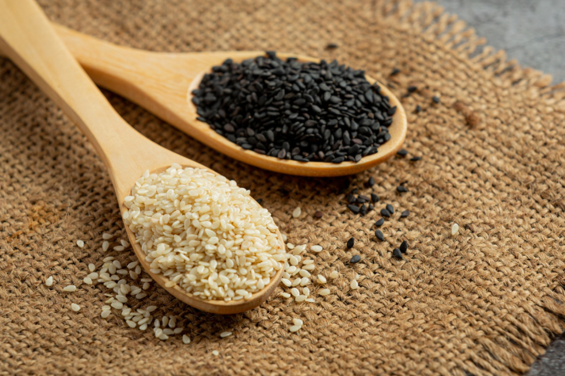 Sesame seeds in a small ceramic bowl with a mortar and pestle, symbolizing their ancient use and nutritional value.