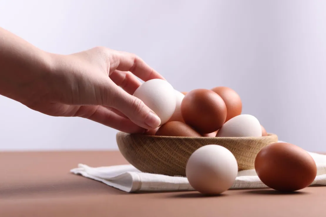 A carton of eggs with several eggs arranged beside it, illustrating the question of daily egg intake limits