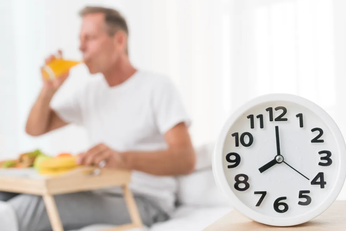 A person having an early breakfast with a clock showing morning hours, symbolizing reverse fasting