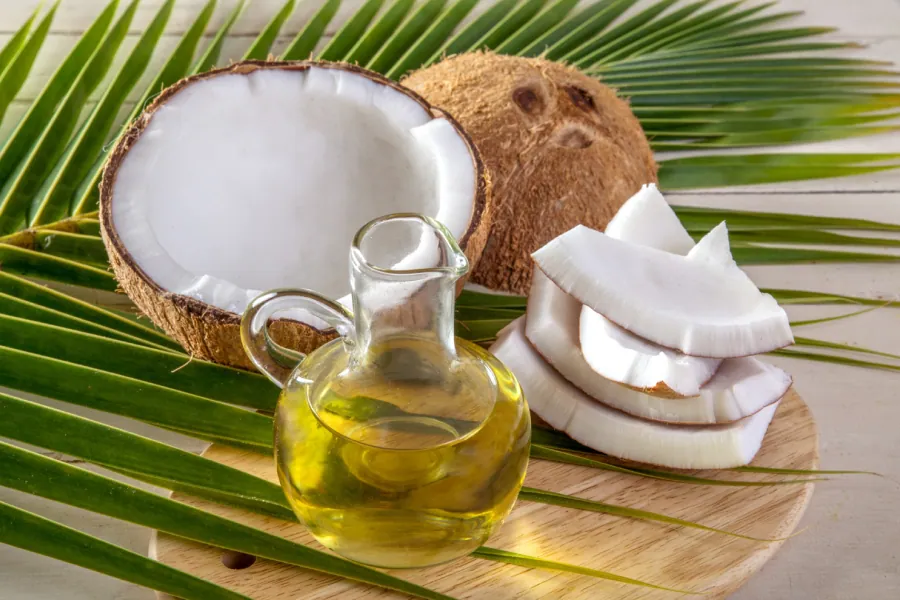 Fresh coconuts and coconut oil in a glass jar, highlighting its tropical origin.