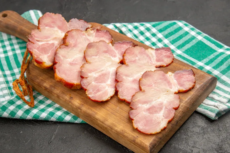 Thin slices of lean cured turkey-style bacon arranged on a wooden serving board